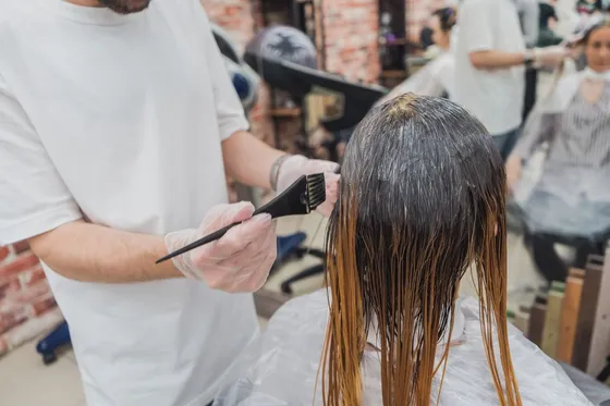 Estilista aplicando color en el cabello de una clienta en el salón